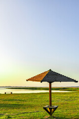 One wooden umbrella on an empty beach near the lake.