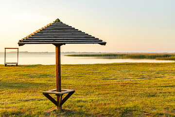 One wooden umbrella on an empty beach near the lake.