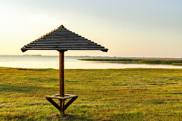 One wooden umbrella on an empty beach near the lake.