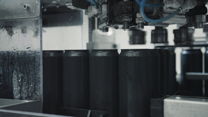 In a modern beverage production facility, automated machinery efficiently processes a row of sleek black aluminum cans, ensuring precise filling and sealing for high quality products