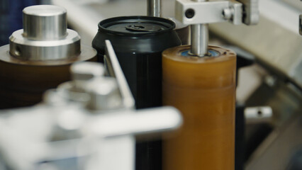 Aluminum beverage can being processed by labeling machine on a production line in modern beverage...