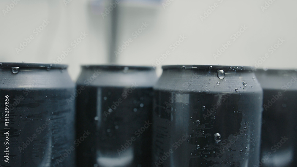 Poster refreshing and ice cold, black aluminum cans with condensation droplets stand in a row, creating a v