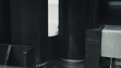 Aluminum cans with condensation droplets moving on a conveyor belt inside a bottling factory, close...