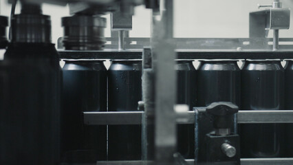 Aluminum cans moving along a conveyor belt in a beverage production facility, undergoing essential filling and sealing processes within a highly automated manufacturing environment