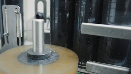 Automated labeling machine applying adhesive labels to black aluminum cans on a conveyor belt in a beverage production facility, demonstrating modern packaging technology and industrial efficiency