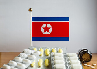 Flag of North Korea with Pills and Capsules. Pharmaceutical Concept

