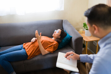 Patient talking with psychologist during therapy session on sofa