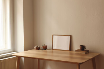 Autumn interior still life. Cup of tea, coffee, old books and pumpkins on wooden table at window. Horizontal picture frame, poster mockup. Home office. Minimal Scandi interior. Thanksgiving home decor