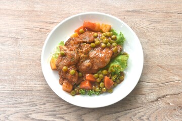 braised pork steak in gravy sauce stew with vegetable topping fresh lettuce on plate