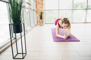 Active woman practicing yoga in a cozy home studio with bright natural light and modern decor while...