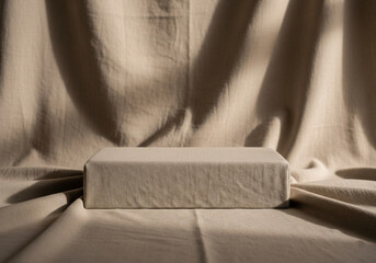 Minimalist product display podium on a draped beige fabric background with natural light and shadows. An empty stage for presentation.