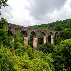 Fototapeta premium A weathered stone arch bridge through a lush valley