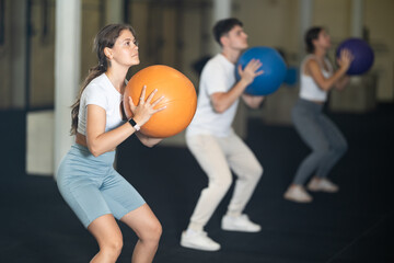 Crossfit in the gym, young people throwing a ball into a hoop