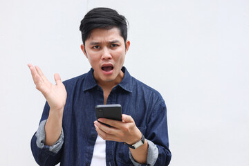 close up young asian man with stress emotion on face with during hold smartphone to reading about bad comment on social media application or read news and rumor in home for people lifestyle concept