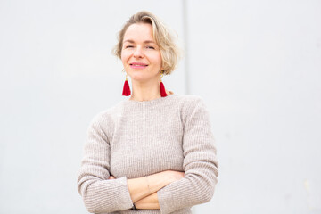 confident woman in a sweater stands with arms crossed against white background