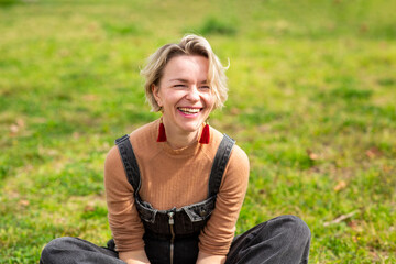 Obraz premium Laughing woman sitting on the grass in sunny park