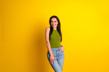 Smiling young woman in stylish casual attire posing against a vibrant yellow background showcasing...