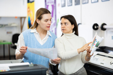 Women printing office workers discussing usage of test page for printer.