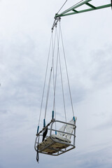 A Suspended Seat from an Amusement Ride against a Backdrop of Gray Sky