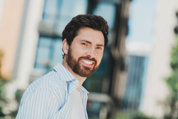 Portrait of a cheerful young man enjoying an urban setting on a sunny day, exuding confidence and...