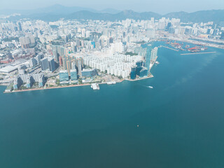 Fototapeta premium Aerial view of central Hong Kong, China. Expansive cityscape shows dense urban area meeting the sea. Buildings stretch towards distant mountains.
