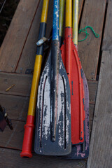 Colorful Collection of Used Paddles Resting on a Wooden Deck Background Evoking Memories of...