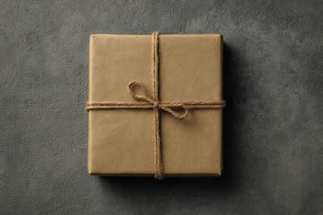 Gift box wrapped in plain kraft paper with jute rope on dark surface