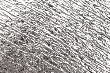 Texture of crumpled silver foil. Foil with dents, folds and wrinkles