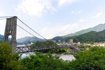 桃介橋,吊り橋,長野県,南木曽町,木曽川,橋,歴史的建造物,文化財,観光地,山,山並み,緑,森林,自然,川,河川,石垣,田舎,風景,夏,空,雲,日本,景勝地,旅行,観光,建築,土木,橋梁,集落,田園,渓谷,川辺,緑地,岩,