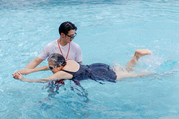 asian man trainer teach senior adult to exercise swimming at sport club swimming pool, active...