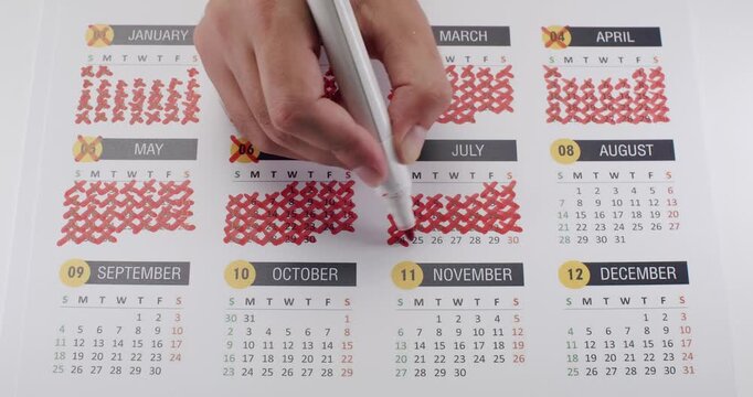 Close-up of a hand marking and crossing off days on a calendar. Concept of time management, goal setting, and tracking progress throughout the year. Illustrates planning and organization.