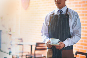 Young man barista serving a cup of coffee. selected focus