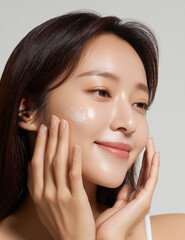 Side-angle view of Korean woman applying lotion to face with upward motions