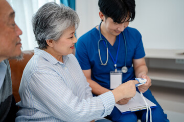 Obraz premium senior woman using pulse oximeter to measure blood oxygen instructed by physiotherapist. home caregiver nurse visit retire couple patient for health check up recovery process medical service