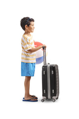 Boy with a beach ball standing with a suitcase