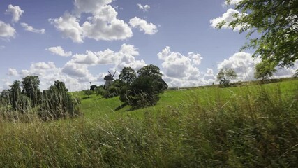Landscape with a vintage mill on the hill. Summer sunny day. High hill against the background of a blue sky. Latvia blue sky. Latvia. 