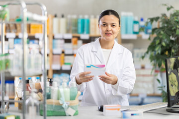 Female pharmacist of Asian appearance works at a computer in a pharmacy. Saleswoman in the pharmacy...