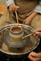 Craftswoman applying paint to ceramic dish 