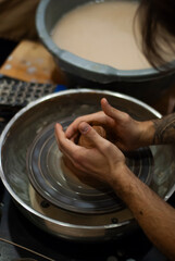 Hands shaping wet clay on a spinning pottery wheel 