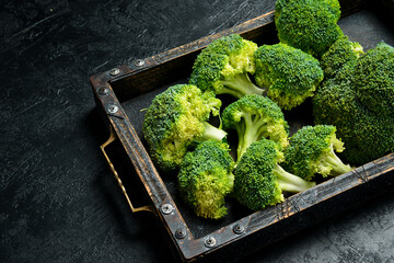 Fresh organic green broccoli in a wooden box. On a black stone background. Close up. Green...