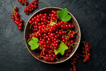 Ceramic bowl with fresh red currant berries. On a dark concrete background, close-up.