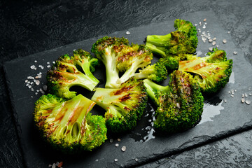 Grilled broccoli with balsamic sauce on a black slate plate. Electric grill. On a black stone...