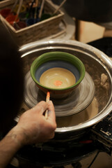 Artist painting clay mug with fine brush 