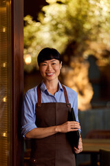 Smiling Server Standing Inside Elegant Restaurant Holding Menu Folder