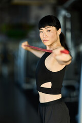 Focused Woman Stretching Resistance Band During Workout at a Fitness Studio