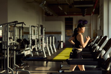 Woman Running on Treadmill in a Spacious Gym During Golden Hour