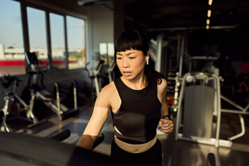 Focused Woman Jogging on Treadmill in a Bright Fitness Gym