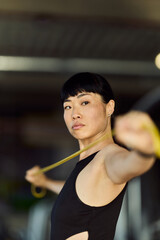 Focused Woman Stretching with Resistance Band at Spacious Fitness Gym