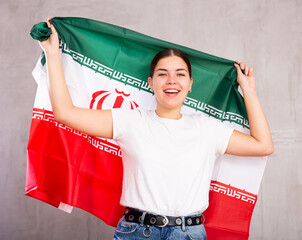 Young positive woman holding national flag of Iran in her hands