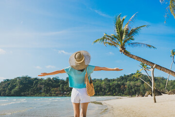 Happy traveler asian woman with hat relax and open arm on Klong chao beach at day in Koh Kood Trat Thailand Summer travel holiday vacation concept